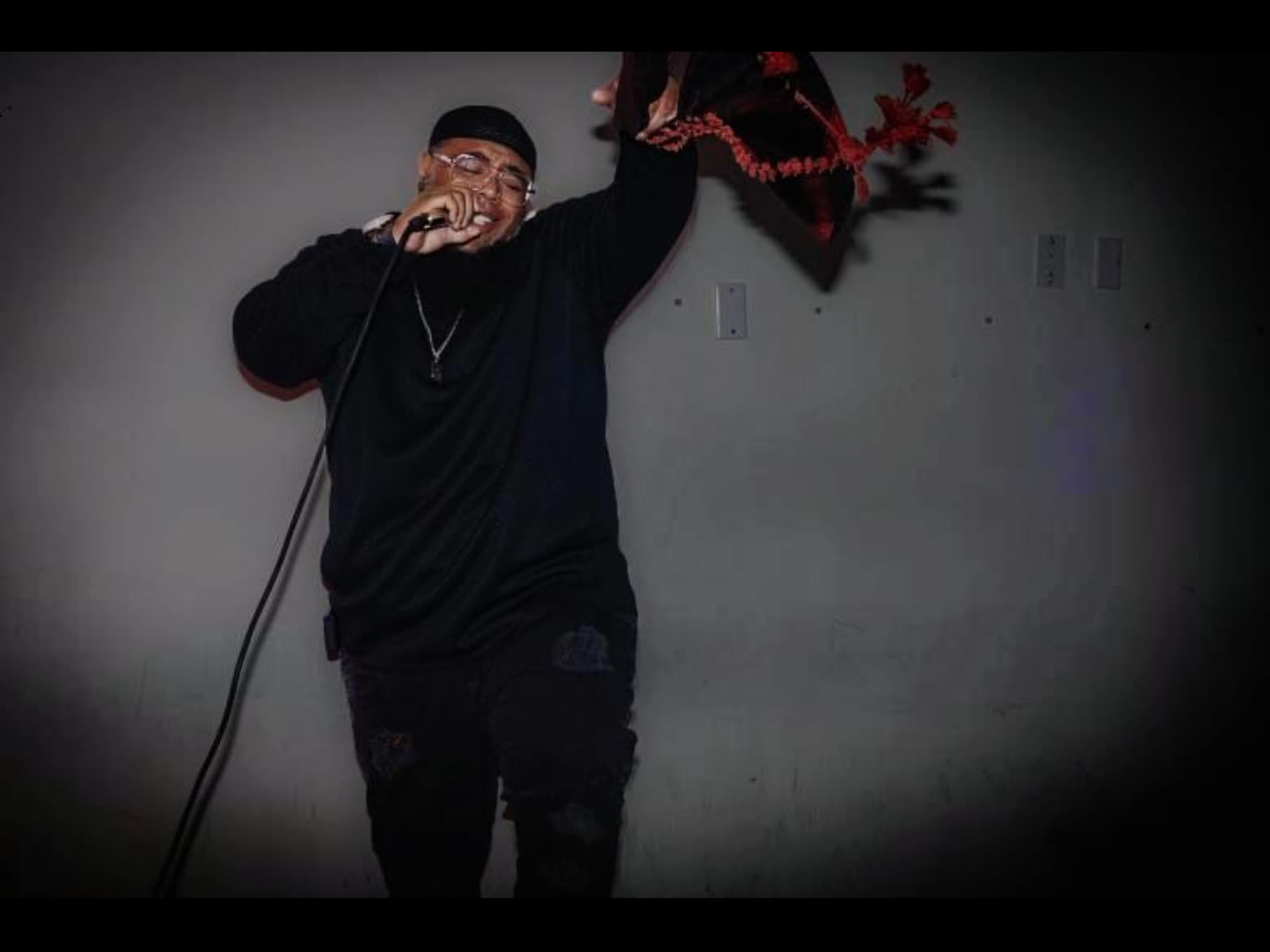 Barrz performing with a handheld mic, free arm raised mid-verse
